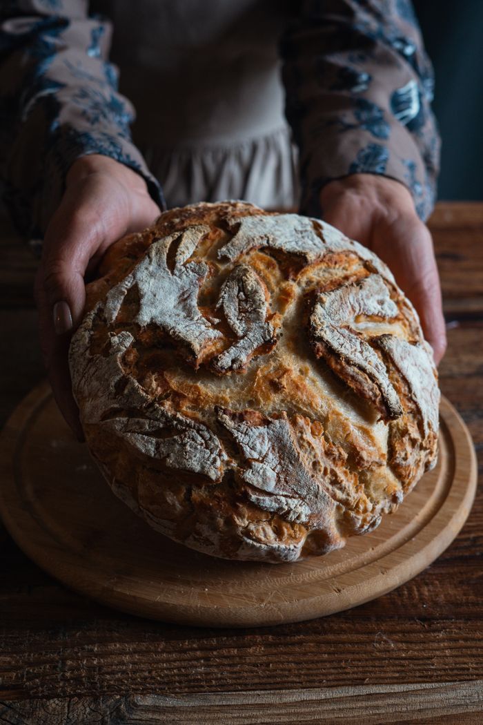 A close-up of rustic, freshly baked bread placed on a wooden table, ideal for artisan food themes.