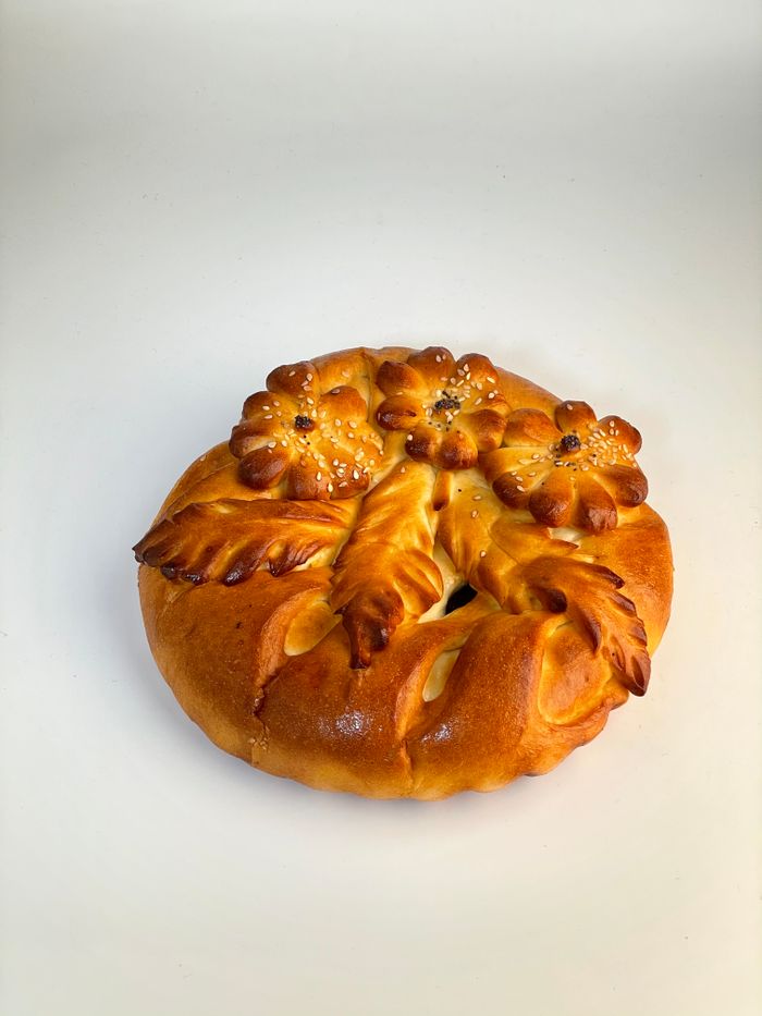 A beautifully baked loaf with intricate floral decorations on a white backdrop.